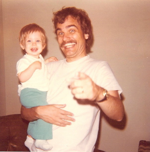 Jim holding a young child and smiling